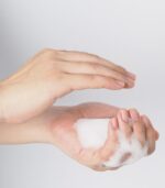Hand washing gesture with foaming hand soap on white background.